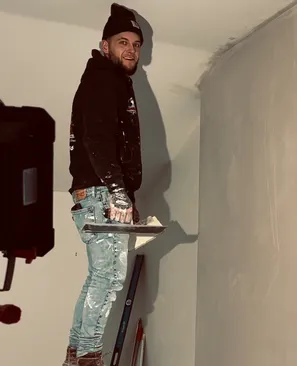 Patriot Plastering worker sanding wall