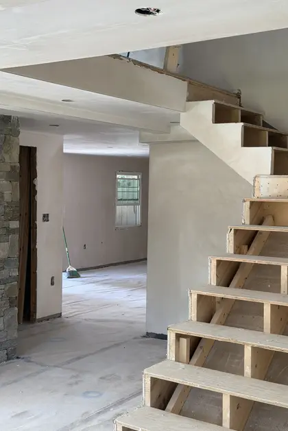 newly plastered staircase beside a stone fireplace