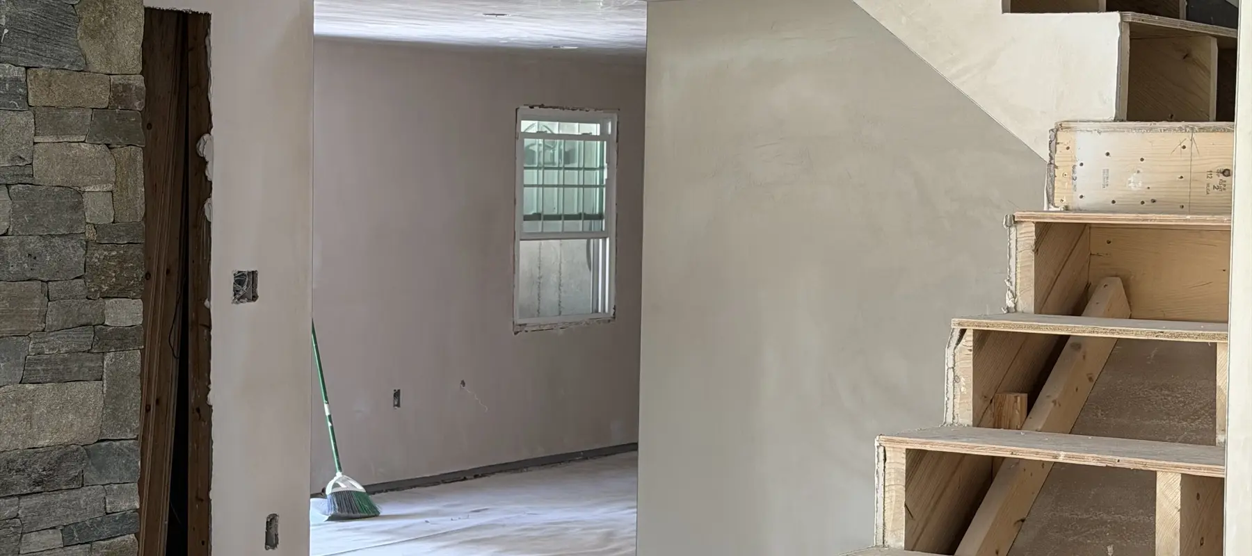 Smooth plaster walls around a staircase and stone fireplace