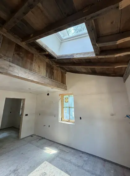 Plastered walls beneath exposed timber framing and a skylight